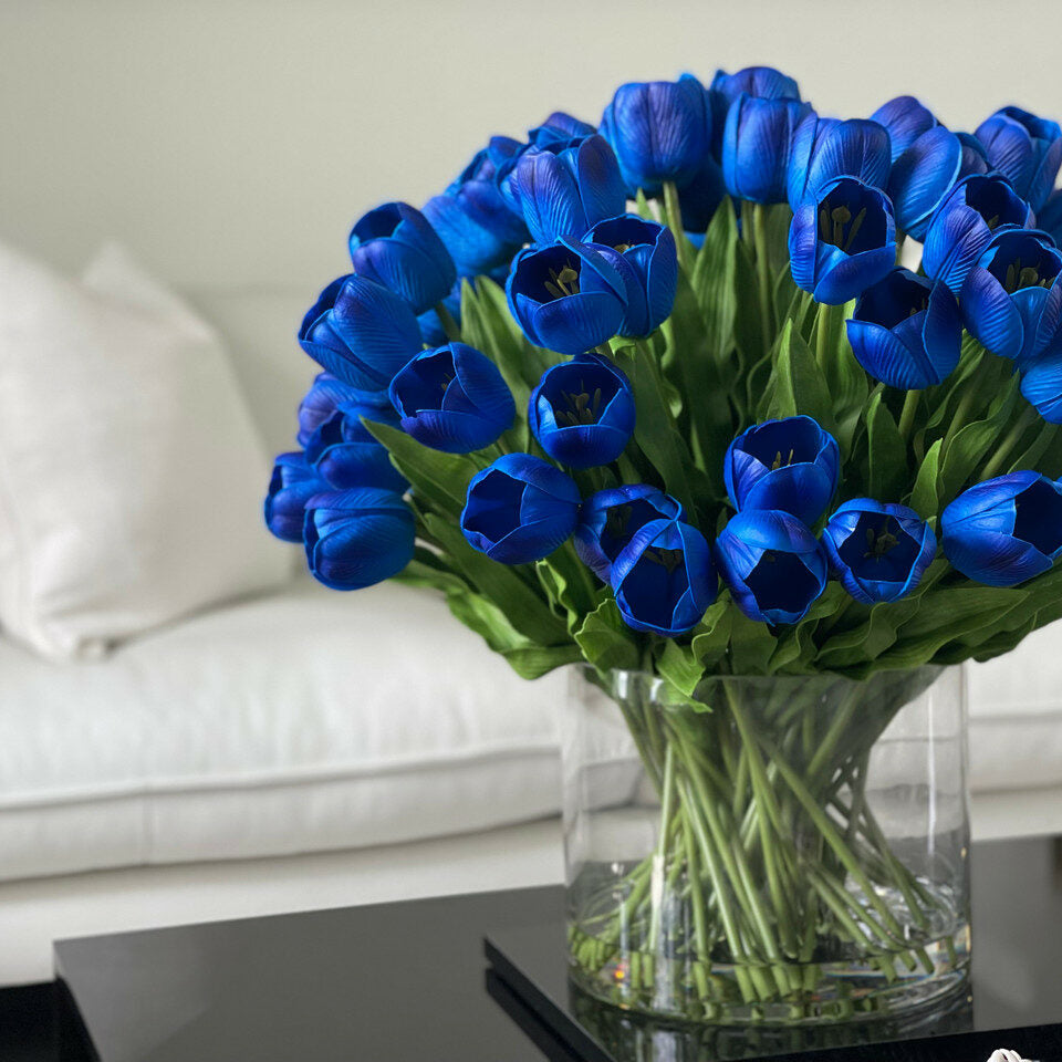 Arrangement de tulipes bleues dans grand vase cylindrique