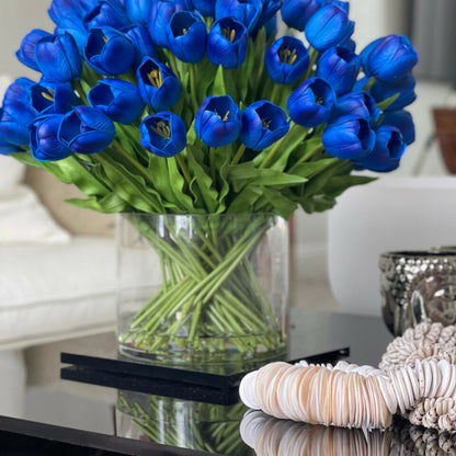 Arrangement de tulipes bleues dans grand vase cylindrique