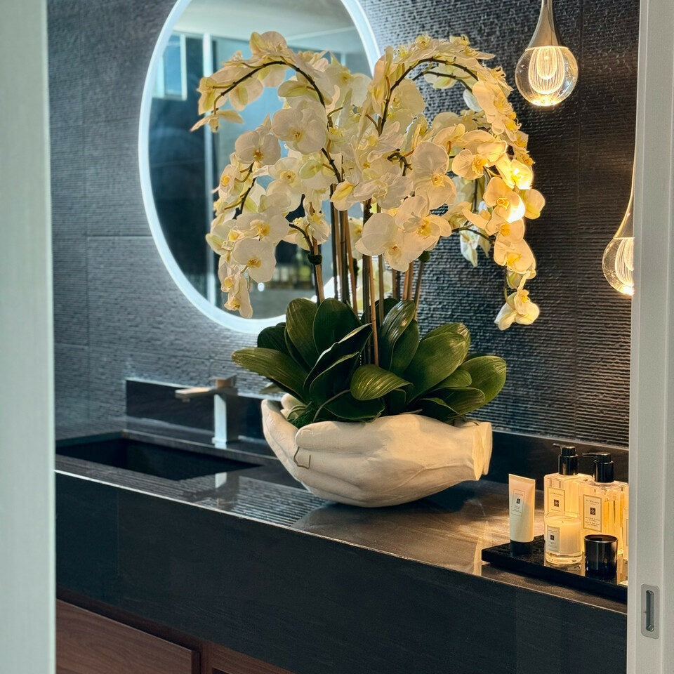 Orchidées Phalaenopsis blanches dans vase sculpture mains ouvertes